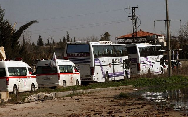 Syrian people on two buses followed by the Syrian Arab Red Crescent's vehicles evacuate the battleground city of Homs, Friday, February 7, 2014 (photo credit: AP)