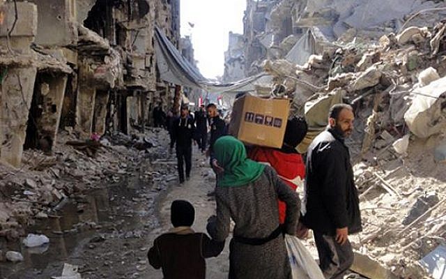Residents of Syria's besieged Yarmouk Palestinian refugee camp carry food parcels, February 1, 2014 (photo credit: UNRWA/AFP)