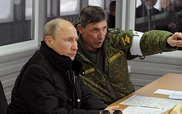Russia's President Vladimir Putin (L) listens to the head of the Russian army's main department of combat preparation, Ivan Buvaltsev (R), while observing military exercises at the Kirillovsky firing ground in the Leningrad region, Monday, March 3, 2014. (photo credit: Mikhail Klimentyev/AFP)