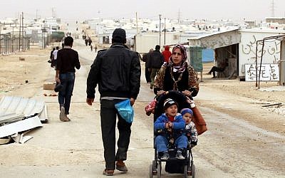 A Syrian refugee woman pushes a stroller at the Zaatari refugee camp, near the Jordanian border with Syria, on March 8, 2014. (photo credit: AFP/KHALIL MAZRAAWI)