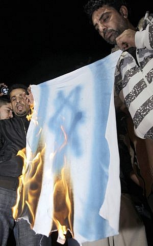 A Jordanian man burns a copy of the Israeli flag during a protest in front of the Israeli embassy, on March 10, 2014. (photo credit: AFP/Khalil Mazraawi)
