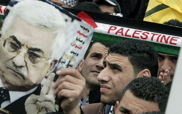 A man holds up an image of Palestinian Authority President Mahmoud Abbas as Palestinians rally in the center of the West Bank city of Nablus in support of Abbas during his visit to Washington, Monday, March 17, 2014. (photo credit: Jaafar/Ashtiyeh/AFP)