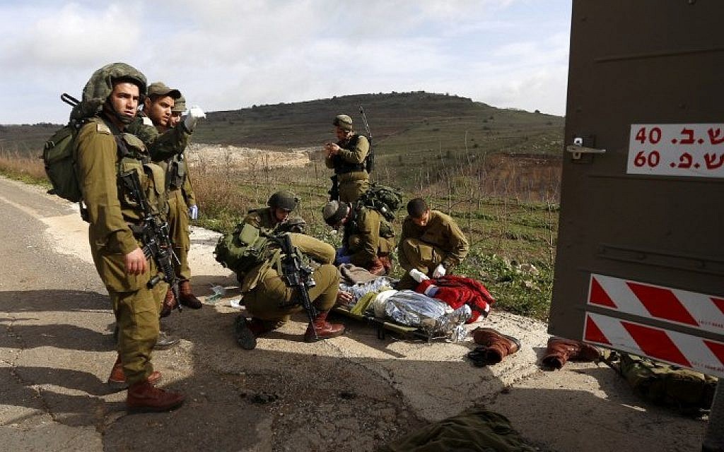 IDF soldiers prepare to evacuate a comrade injured in a blast on the border with Syria, near the village of Majdal Shams on Tuesday, March 18, 2014 (photo credit: AFP/Jalaa Marey)