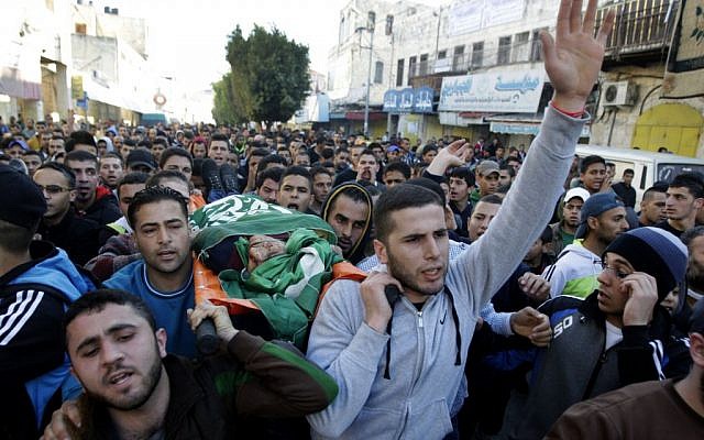 Palestinians carry the body of Hamas terror suspect Hamza Abu el-Hija, who was killed in a raid by Israeli troops, during his funeral procession, in the West Bank refugee camp of Jenin, Saturday, March 22, 2014. (photo credit: AP Photo/Mohammed Ballas)
