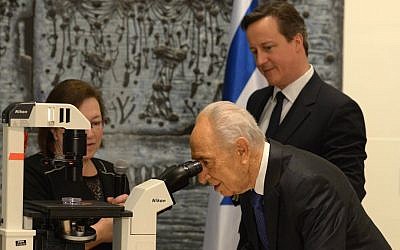 President Shimon Peres examines embryonic stem cells through a microscope during a presentation for him and British Prime Minister David Cameron from Dr. Sharona Even-Ram of the Hadassah medical Center about how stem cells can be used to treat Parkinson's disease. (Photo credit: Mark Neiman/GPO)