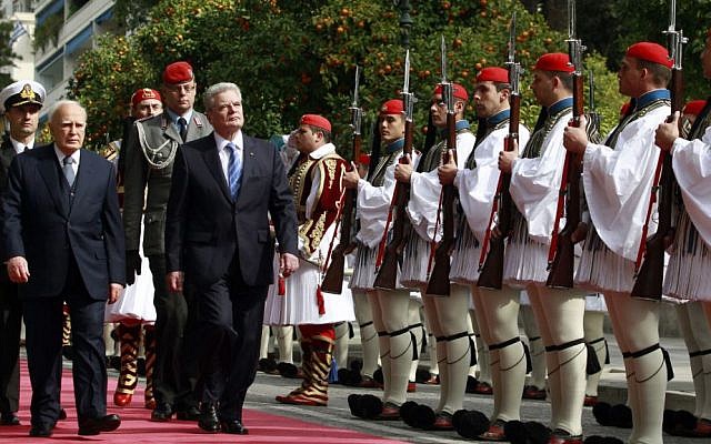 Greek President Karolos Papoulias, left, and his German counterpart Joachim Gauck, right, inspect a presidential guard during an official welcome ceremony outside the presidential palace, in Athens , on Thursday, March 6, 2014. (AP Photo/Kostas Tsironis)