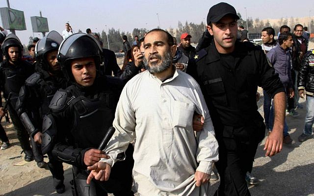 Illustrative: In this Wednesday, January 8, 2014 file photo, Egypt's riot police officers arrest a man, center, following clashes between supporters of Egypt's ousted president Mohammed Morsi and riot police in Cairo, Egypt. (photo credit: AP Photo/Ahmed Gomaa, File)