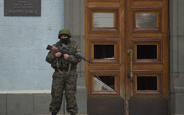 An unidentified man guards the entrance to a local government building in Simferopol, Ukraine, on Saturday, March 1, 2014. (AP Photo/Ivan Sekretarev)
