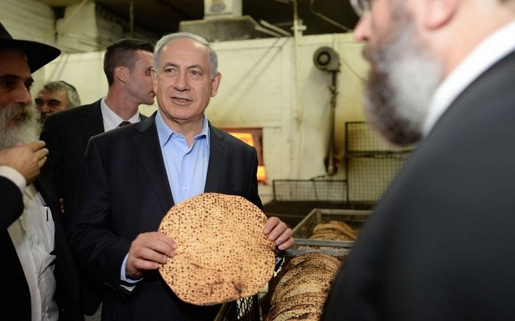 Prime Minister Benjamin Netanyahu holding a shmura matzah at a matzah factory in Kfar Chabad, Israel, prior to the upcoming Jewish holiday of Passover,  April 1, 2014. (Kobi Gideon/GPO/Flash90)