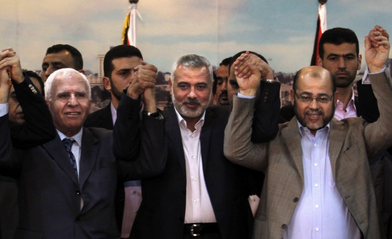 (From L to R) Palestinian Fatah delegation chief Azzam al-Ahmad, Hamas prime minister in the Gaza Strip Ismail Haniyeh and Hamas deputy leader Moussa Abu Marzouk pose for a photo as they celebrate in Gaza City on April 23, 2014, after West Bank and Gaza Strip leaders agreed to form a unity government within five weeks. (photo credit: AFP/Said Khatib)