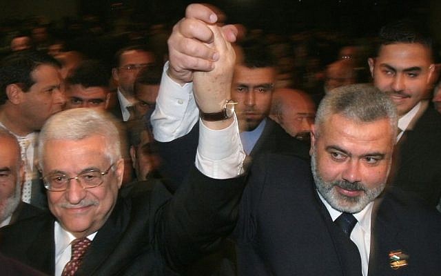 Palestinian Authority President Mahmoud Abbas, left, and then Hamas prime minister Ismail Haniyeh, right, raise their linked arms as they move through the crowd at a special session of parliament in Gaza City, March 17, 2007. (AP/Hatem Moussa/File)