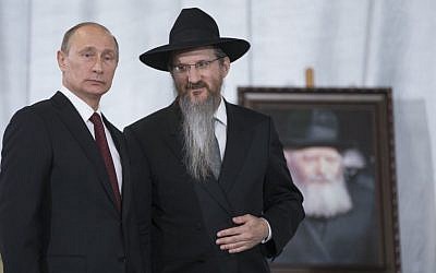 Russian President Vladimir Putin speaks with Russia's Chief Rabbi Berel Lazar in front of a portrait of Rabbi Menachem Mendel Schneerson as he visits the library of the Schneerson family of Hasidic rabbis in the Jewish Museum in Moscow, Thursday, June 13, 2013. (photo credit: AP Photo/Alexander Zemlianichenko)