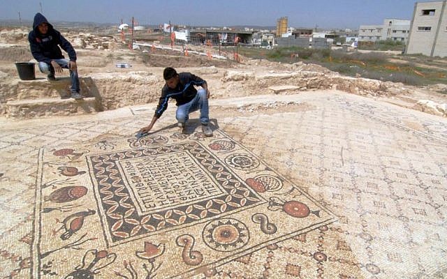 A man unveils Greek inscriptions as he cleans a Byzantine mosaic floor that decorated a monastery and that was discovered during infrastructure work in the Bedouin village of Hura, Tuesday, April 1, 2014. (photo credit: Flash90)