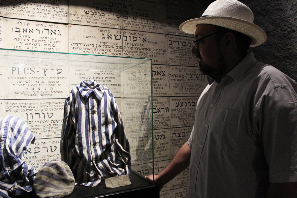 Ilan Goodman, curator at the Chamber of the Holocaust, points out a uniform from a concentration camp, one of the items housed at the chamber. (Photo credit: Rebecca McKinsey/The Times of Israel)