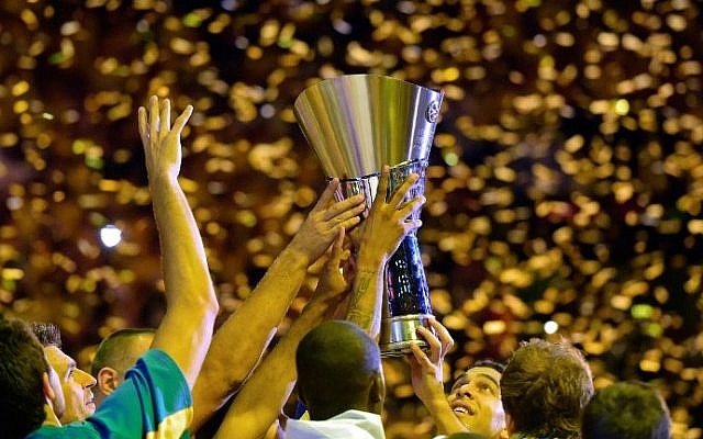 Maccabi Tel Aviv players gather around the trophy as they celebrate their victory after their Euroleague 2014 Gold medal Final Four basketball game on May 18, 2014 at the Mediolanum stadium in Assago. (photo credit: Olivier Morin/AFP)