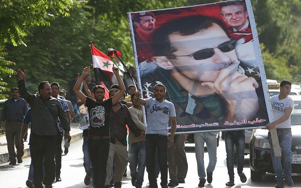 Syrian citizens who live in Lebanon shout slogans and carry a big portrait of Syrian President Bashar Assad, as they walk towards to the Syrian Embassy to ballot their vote for their presidential elections, in Baabda, east of Beirut, Lebanon, Wednesday May 28, 2014. (photo credit: AP/Hussein Malla)