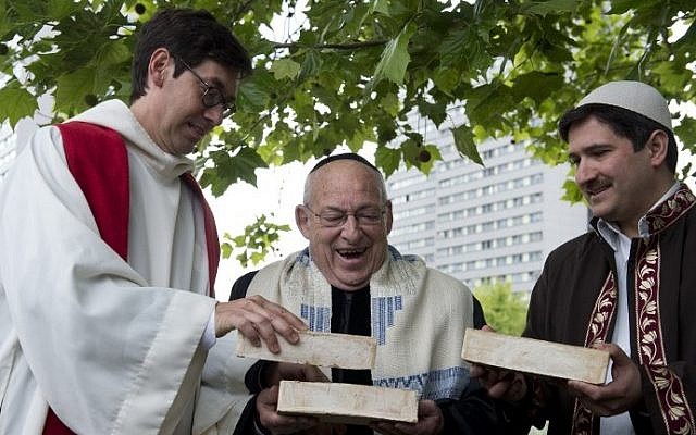 (From L) German Pastor Gregor Hohberg, Israeli Rabbi Tovia Ben-Chorin and German-Turkish Imam Kadir Sanci hold three bricks as they pose for photographers in the vacant lot where they hope to build a multifaith prayer building, in Berlin June 3, 2014 (photo credit: AFP/JOHN MACDOUGALL)