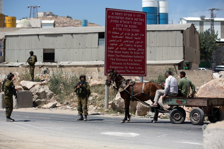Israeli soldiers man a checkpoint in the West Bank city of Hebron on Sunday, June 15, 2014, as Israel broadened the search for three teenagers believed kidnapped by terrorists (photo credit: AFP/MENAHEM KAHANA)