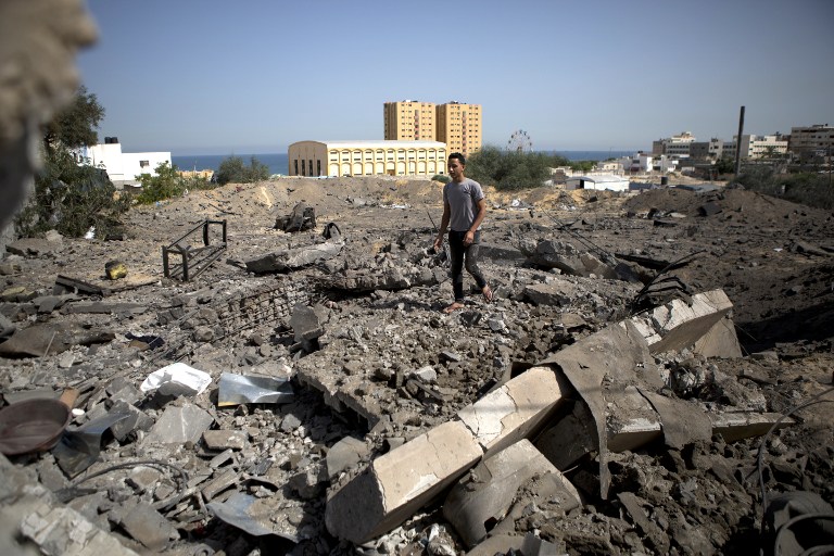 A Palestinian man walks on the rubble past a crater following an air strike by the Israeli Air Force on Gaza City, on Monday, June 16, 2014 (photo credit: AFP/MOHAMMED ABED)