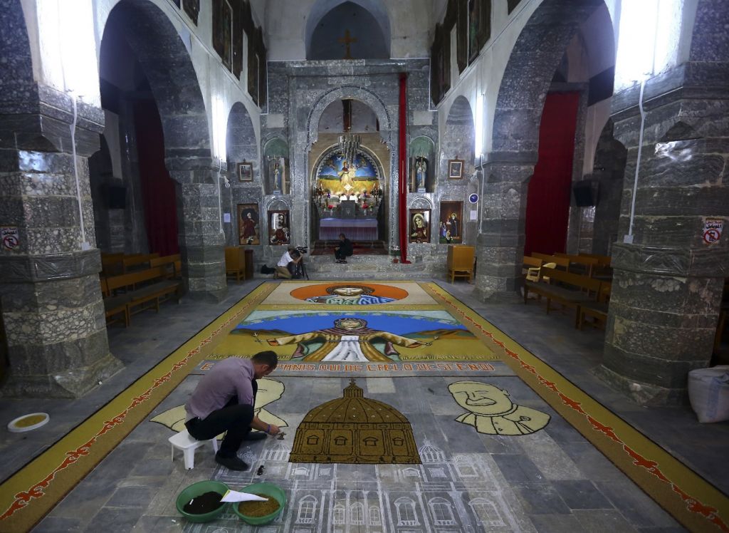 An Iraqi works on a temporary mosaic of Christian symbols made from the area's produce, including wheat, beans and lentils to commemorate an upcoming harvest feast, at the Chaldean Church of the Virgin Mary of the Harvest, in Alqosh,  June 15, 2014. (photo credit: AP)