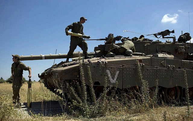 Israeli soldiers load shells into their tank following the first death on the Israeli side of the Golan since the eruption of the Syrian civil war more than three years ago, near the Israeli village of Alonei Habashan, June 22, 2014 (AP/Oded Balilty)