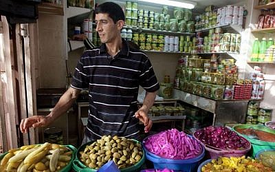 A Palestinian vendor displays food, including pickled vegetables and olives, in preparation for Ramadan at a market in the West Bank city of Hebron, Saturday, June 28, 2014. (photo credit: AP/Majdi Mohammed)
