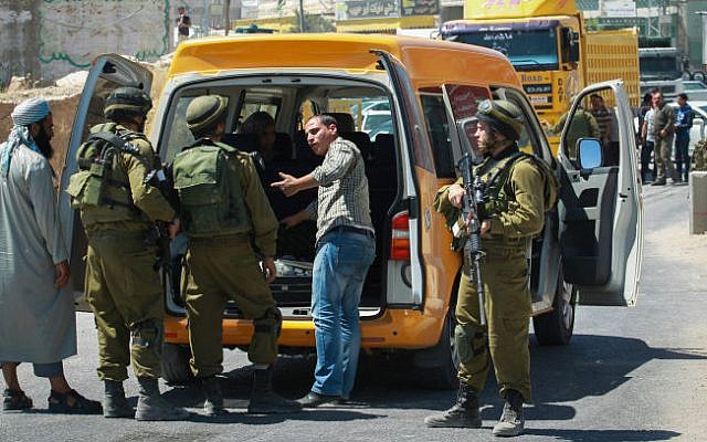 Israeli soldiers search Palestinians, after setting up a checkpoint at the entrance to the industrial zone of Hebron, on June 15, 2014. (photo credit: Hadas Parush/FLASH90)