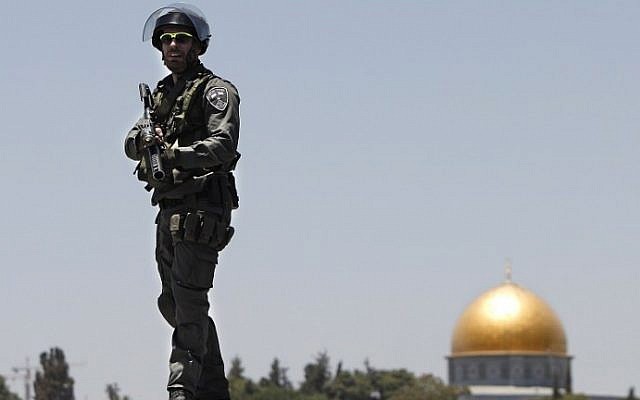 An Israeli policeman stands guard on the top of a building in front of the dome of the Rock in East Jerusalem on July 4, 2014 (Ahmad Gharabli/AFP)
