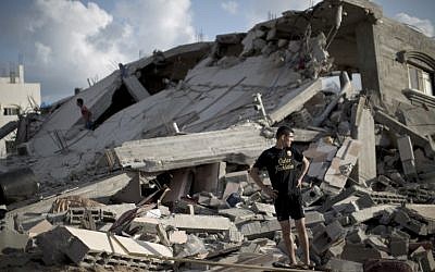 A Palestinian man stands on the rubble of a destroyed building following an Israeli strike on Beit Lahiya, in the northern Gaza Strip on July 15, 2014.  (photo credit: AFP/MAHMUD HAMS)