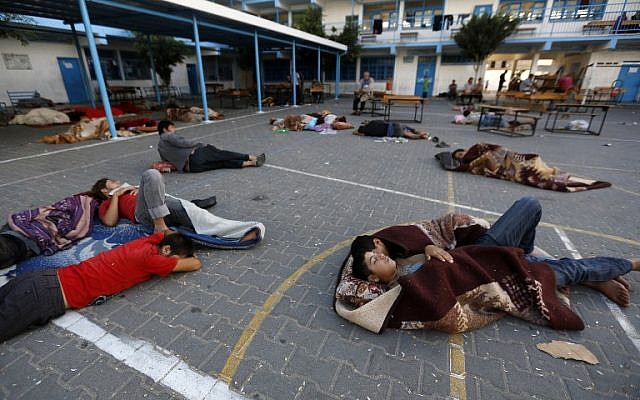 Palestinians sleep in the yard of a UN school in the northern Gaza Strip town of Beit Lahiya early on July 16, 2014, after evacuating their houses near the border with Israel. (photo credit: AFP/MOHAMMED ABED)