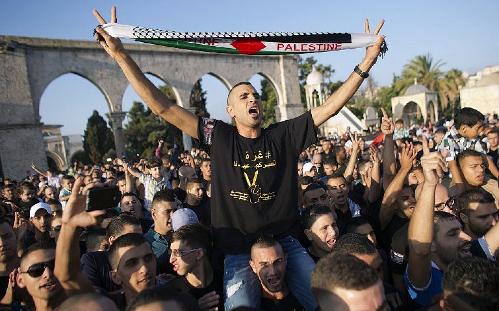 A Palestinian flashes the sign of victory holding a scarf reading 'Palestine' during a demonstration against Israel's military offensive on the Gaza Strip on July 28, 2014, at al-Aqsa mosque compound in the Old City of Jerusalem (photo credit: AFP/AHMAD GHARABLI)