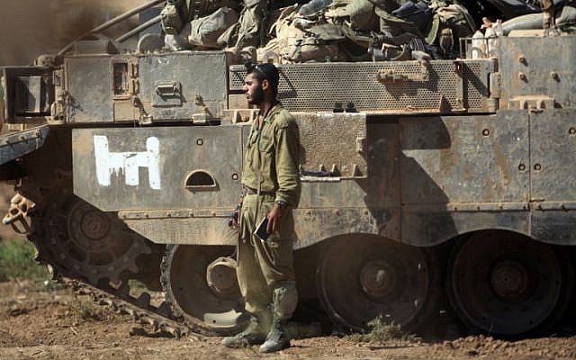 An Israeli soldier prays next to an armored personnel carrier near the Israel-Gaza border, on July 30, 2014. (AFP/David Buimovitch)