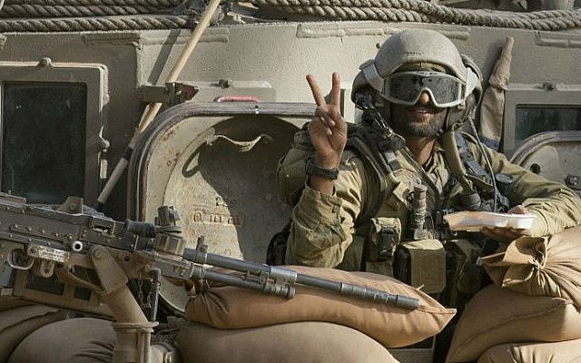An Israeli soldier flashes the "V" for victory sign from an armored personnel carrier (APC) at an army deployment area near Israel's border with the Gaza Strip on July 17, 2014 (photo credit: AFP/ Jack Guez)
