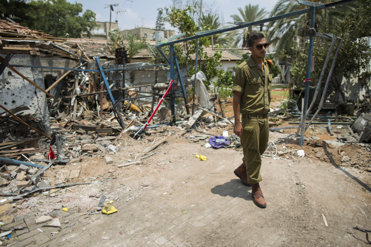 An Israeli soldier looks at the damage to a house following a rocket attack from the Gaza Strip on the town of Yehud, near Ben Gurion Airport, on July 22, 2014. (photo credit: Yonatan Sindel/Flash90)
