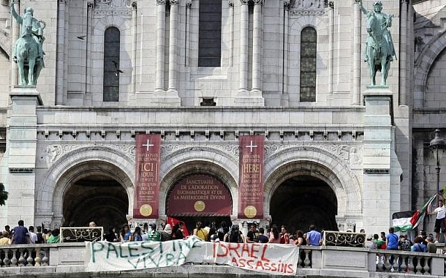Pro-Palestinian demonstrators hold banners reading: "Palestine will live" and "Israel assassins," in front of the Sacre Coeur basilica at Montmartre in Paris, Saturday July 19, 2014. (photo credit: AP Photo/Remy de la Mauviniere)