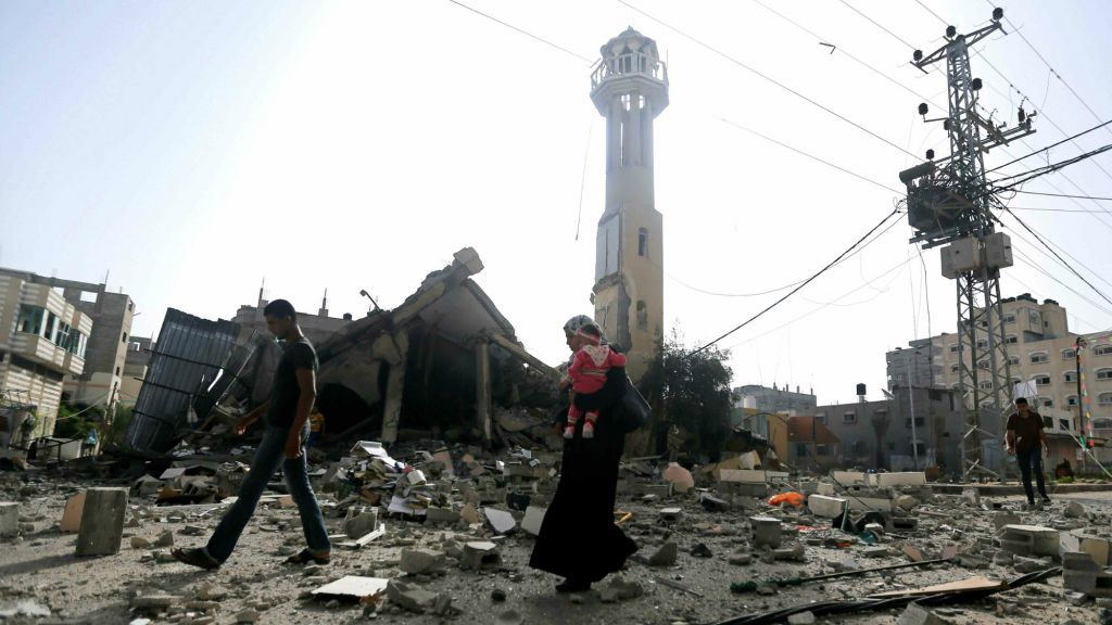 Illustrative photo of Palestinians walking past the ruins of a mosque after that was hit by an Israeli missile strike, in the central Gaza Strip (AP Photo/Hatem Moussa)