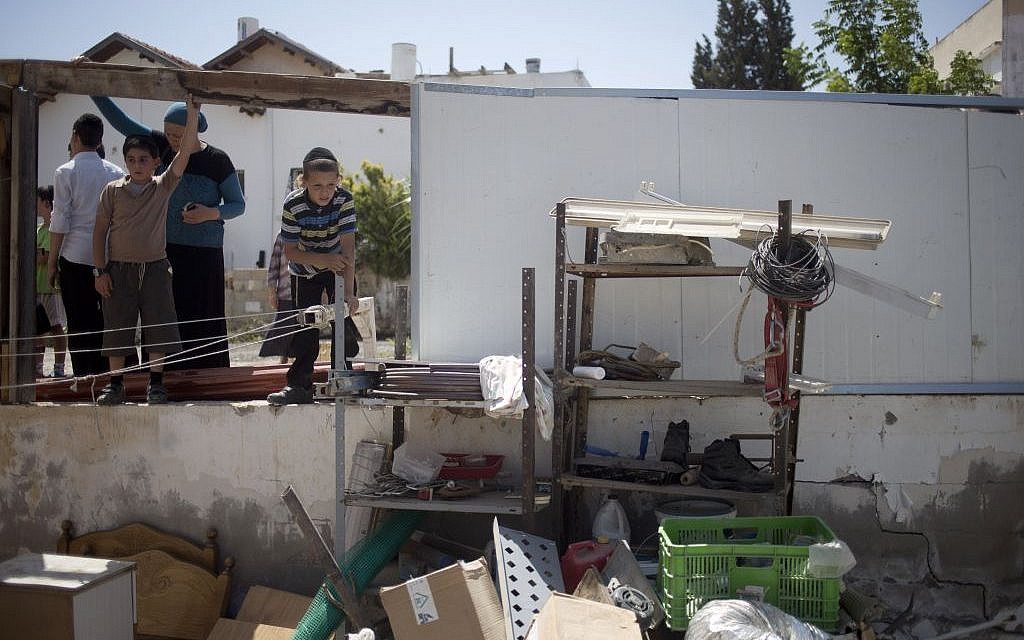 Residents look at damage caused by a rocket fired by Palestinians from inside Gaza Strip after it hit in Netivot, southern Israel, Thursday, July 10, 2014 (photo credit: AP/Ariel Schalit)