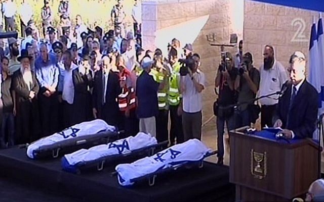Avshalom Kor speaking aside the flag-draped bodies of Naftali Fraenkel, Gil-ad Shaar and Eyal Yifrach at their funeral Tuesday. (Screen capture: Channel 2)