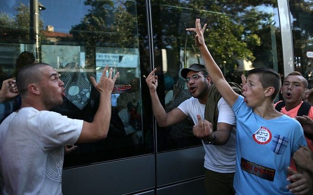 Right wing Jewish teenagers wearing stickers that say 'Kahana was right' and 'Revenge' seen giving the finger and yelling at Arab women sitting inside the tram in central Jerusalem during a large right wing protest against Arab terrorism, July 1, 2014, in response to the kidnap and murder of three Jewish teens (Nati Shohat/Flash90)