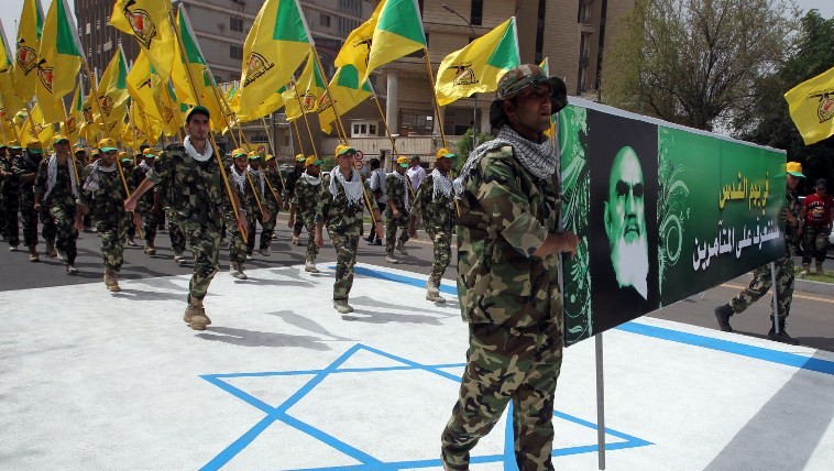 Iraqi Hezbollah members hold up the yellow flags of the Iraqi branch of the Shiite Muslim party and a portrait of Iran's late spiritual guide, Ayatollah Ruhollah Khomeini, as they walk on an Israeli flag painted on theground during a parade marking al-Quds (Jerusalem) International Day on July 25, 2014 in the Iraqi capital Baghdad. (photo credit: AFP/Ali al-Saadi)