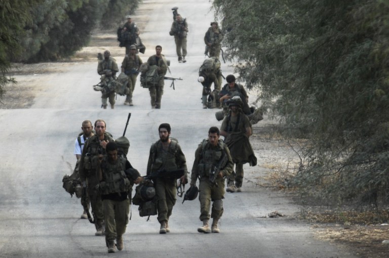 Israeli soldiers walk near the border between Israel and the Gaza Strip as they return from the Hamas-controlled Palestinian coastal enclave on Tuesday, August 5, 2014 (photo credit: AFP/DAVID BUIMOVITCH)