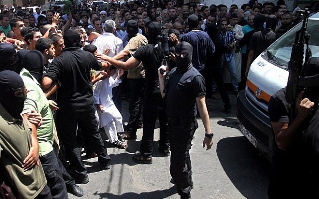 Armed Palestinian masked men push back a crowd of worshippers outside a mosque in Gaza City after Friday prayers on August 22, 2014, before executing 18 men for allegedly collaborating with Israel. (AFP)