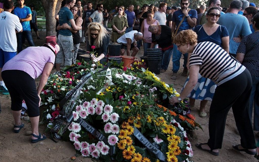 Israeli mourners lay flower wreaths on the grave of Shahar Melamed, 43, who was killed the previous day by Palestinian mortar fire in Kibbutz Nirim near Israel's border with the Gaza Strip, on August 27, 2014 (photo credit: AFP/MENAHEM KAHANA)