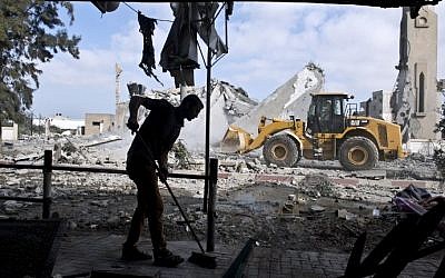 A Palestinian man sweeps the floor of his home that was damaged after a mosque across the street was hit by an Israeli airstrike on August 25, 2014 in Beit Lahia in the northern Gaza Strip. (photo credit: AFP Photo/Roberto Schmidt)