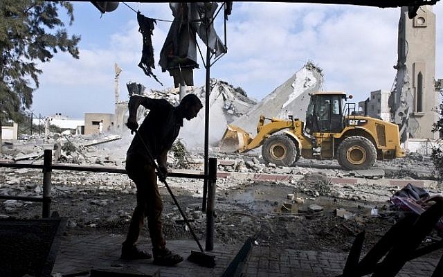 Illustrative photo of a Palestinian man sweeping an area damaged by an explosion in the northern Gaza Strip. (photo credit: AFP/Roberto Schmidt)