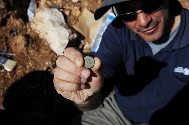 IAA archaeologist Pablo Betzer holds up a Jewish Revolt coin found outside Jerusalem. (photo credit: Vladimir Neichin, IAA)
