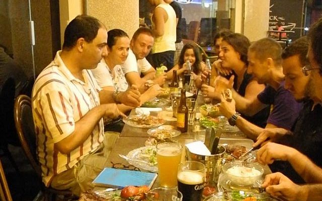 Yigal Rechtman, left, and a full table at Archies bar and restaurant in Ashkelon on Tuesday night.  (photo credit: Melanie Lidman/Times of Israel)