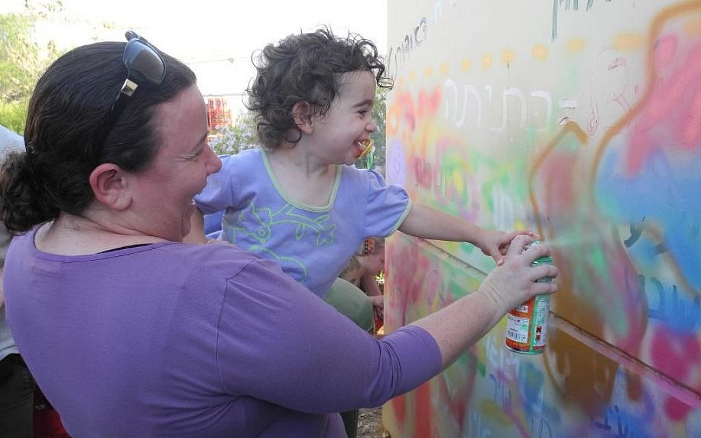 Kibbutz Alumim residents paint a bomb shelter with with members of the art advocacy group Artists 4 Israel on Wednesday. (Melanie Lidman/Times of Israel)