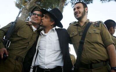 A religious Jewish soldier is embraced by an ultra-Orthodox Jewish family member after a swearing-in ceremony for the  IDF Nahal Haredi unit, at Ammunition Hill in Jerusalem, May 26, 2012 (Miriam Alster/Flash90)