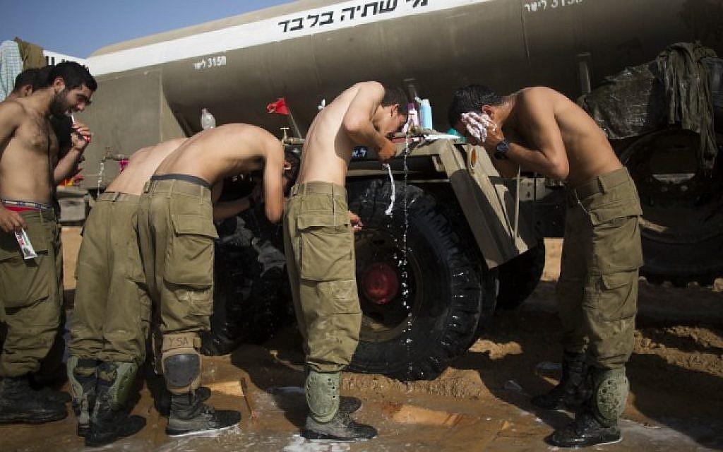 Israeli soldiers take a shower at a deployment area near the border with the Gaza Strip on August 2, 2014. (Yonatan Sindel/Flash90)